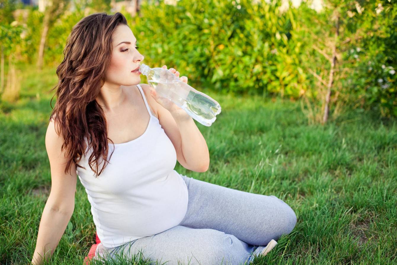 Кидает в жар при беременности. Женщина пьет воду. Питье беременных. Питье воды.