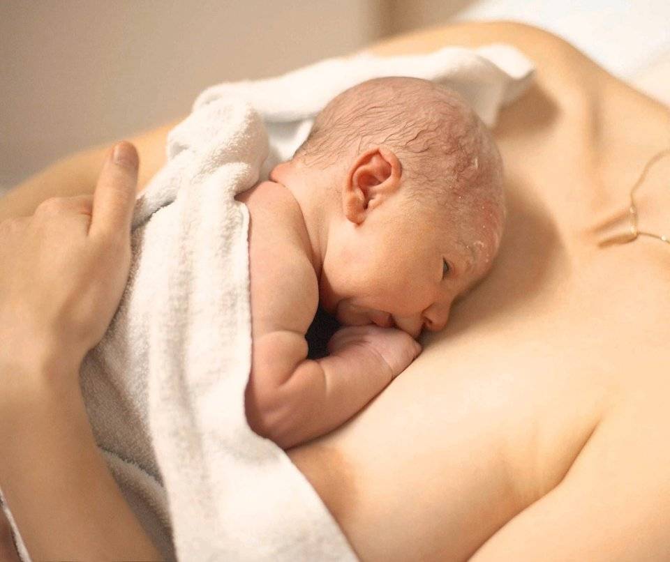 Новорожденный ребёнок висит на груди
