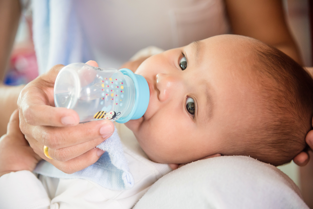Малыш с бутылочкой. Бутылочка для кормления. Вода для новорожденных при грудном вскармливании. Питье для новорожденного ребенка. Пить воду новорожденному ребенку